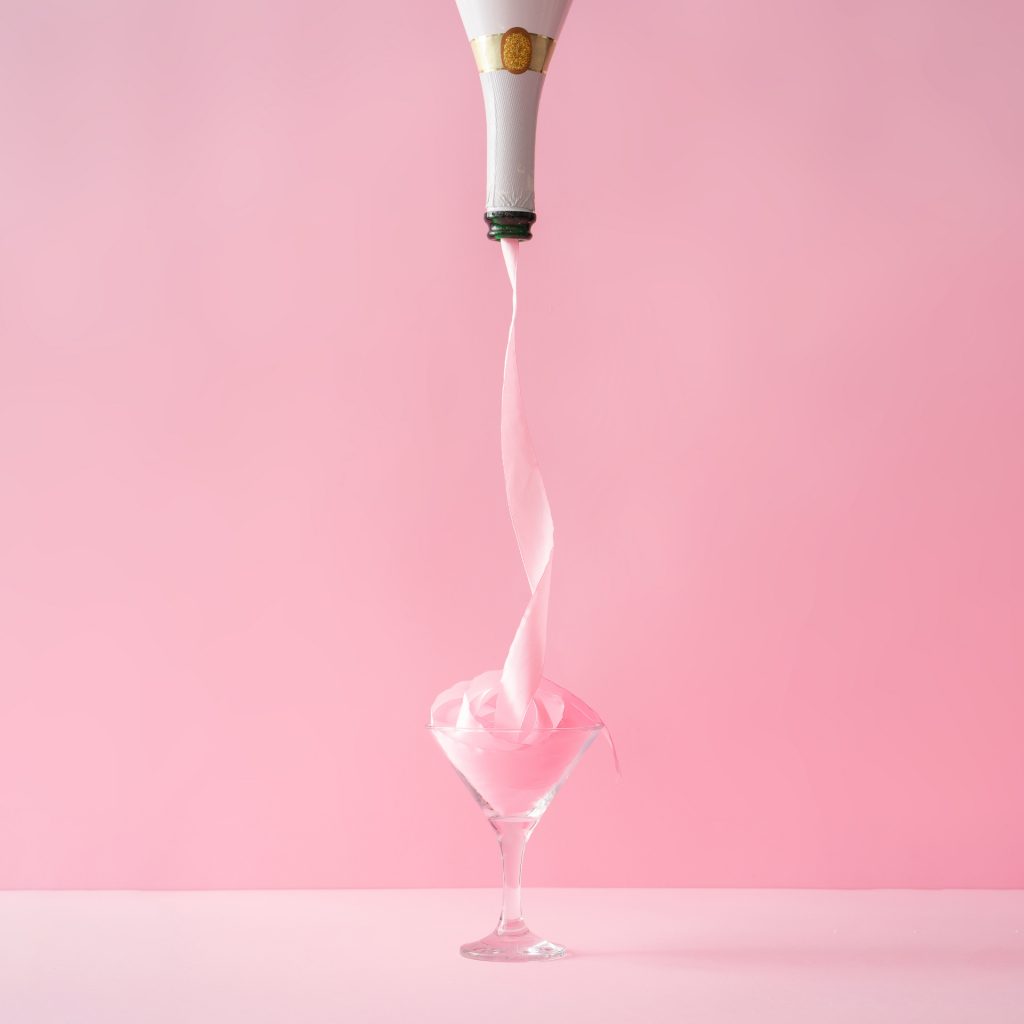 Champagne bottle with pink party ribbon. Minimal Celebration concept.